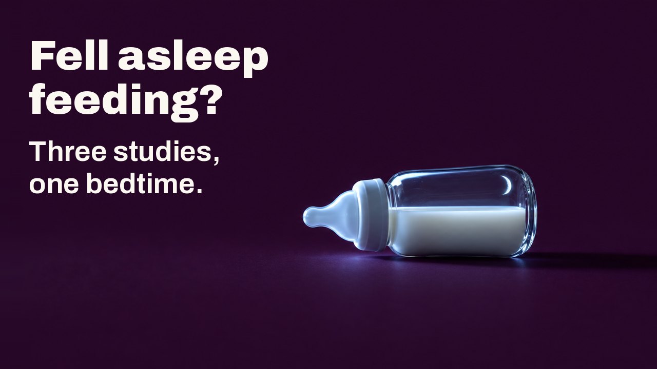 Fell asleep feeding? Three studies, one bedtime. A small glass baby bottle of milk lies on its side on a deep plum ground, lit from one side by the cold light of an unseen screen, a thin crescent moon reflected in the glass.