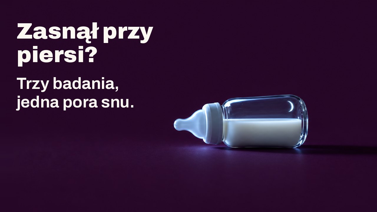Zasnął przy piersi? Trzy badania, jedna pora snu. Mała szklana butelka dla niemowląt z mlekiem leży na boku na głębokim śliwkowym tle, oświetlona z boku zimnym światłem niewidocznego ekranu, w szkle odbija się cienki sierp księżyca.