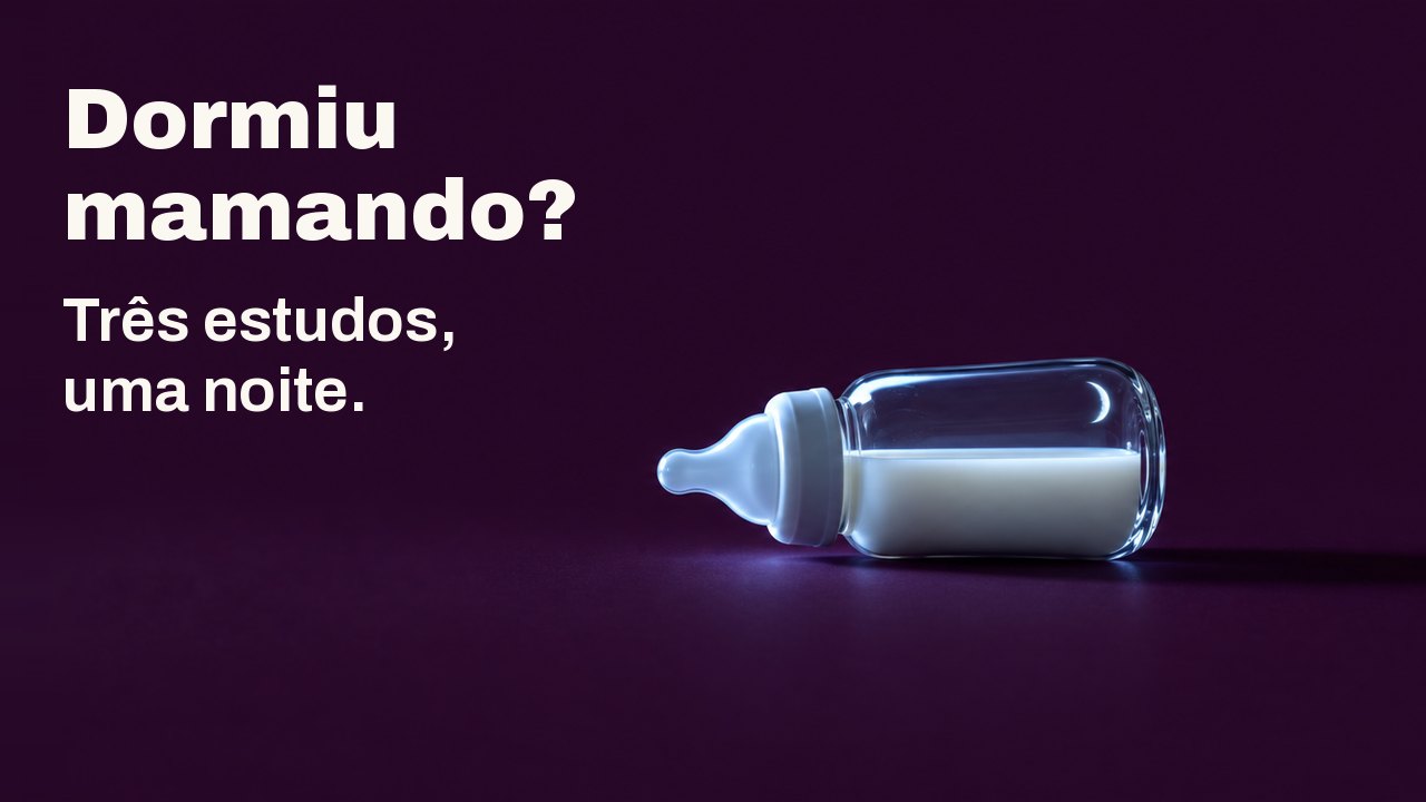 Dormiu mamando? Três estudos, uma noite. Uma pequena mamadeira de vidro com leite está deitada de lado sobre um fundo ameixa profundo, iluminada de um lado pela luz fria de uma tela que não se vê, com uma fina lua crescente refletida no vidro.