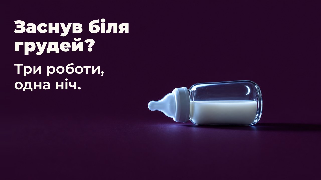 Заснув біля грудей? Три роботи, одна ніч. Маленька скляна дитяча пляшечка з молоком лежить на боці на глибокому сливовому тлі, збоку її освітлює холодне світло невидимого екрана, у склі відбивається тонкий серп місяця.