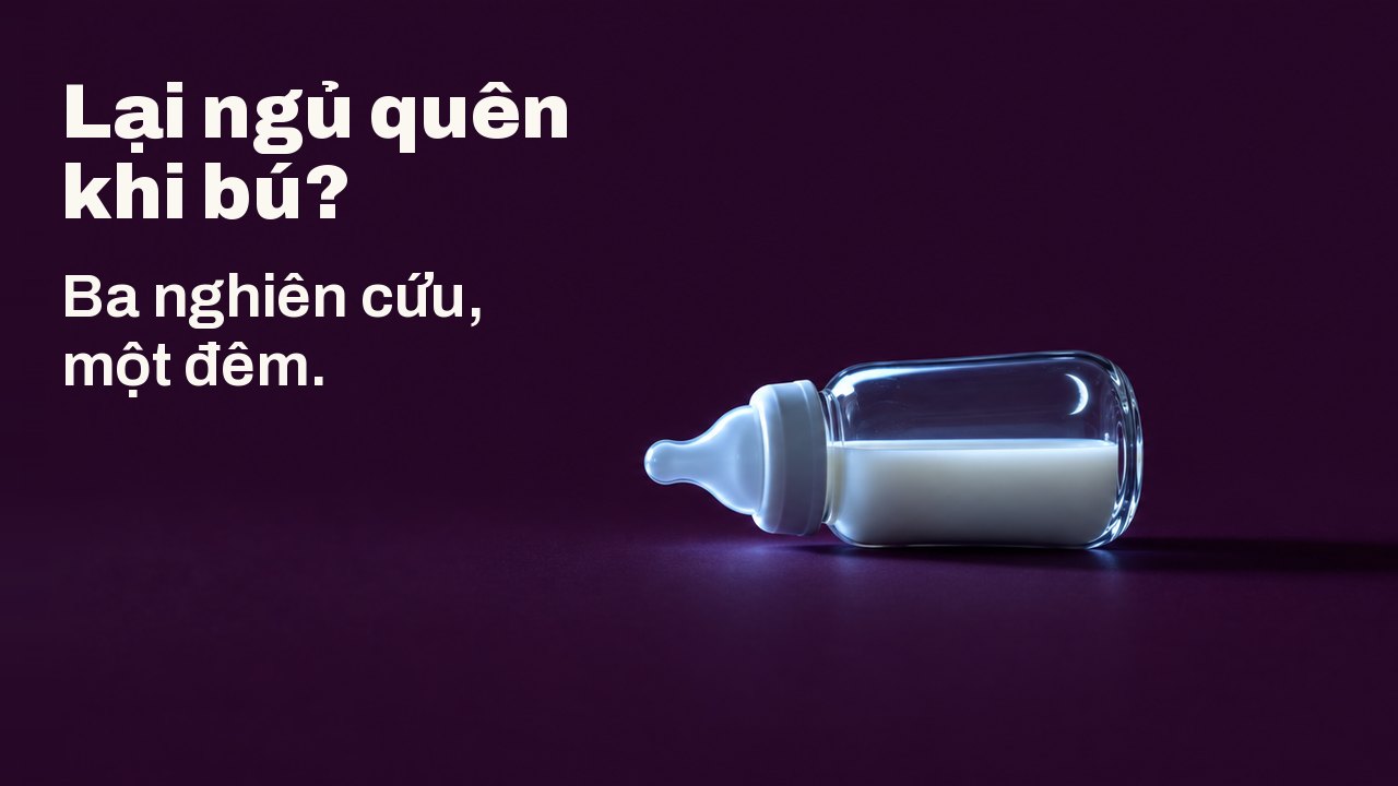 Lại ngủ quên khi bú? Ba nghiên cứu, một đêm. Một chiếc bình sữa thủy tinh nhỏ đựng sữa nằm nghiêng trên nền màu mận chín sẫm, được chiếu từ một bên bởi ánh sáng lạnh của một màn hình không nhìn thấy, vầng trăng lưỡi liềm mảnh phản chiếu trên thủy tinh.