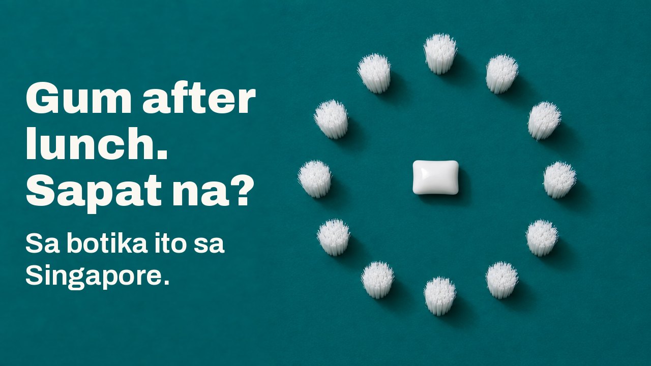 Gum after lunch. Sapat na? Sa botika ito sa Singapore. Tanaw mula mismo sa itaas sa malalim na teal na background: isang puting piraso ng chewing gum ang nasa gitna ng perpektong bilog ng mga puting bungkos ng bristles, parang mukha ng orasan na walang kamay.