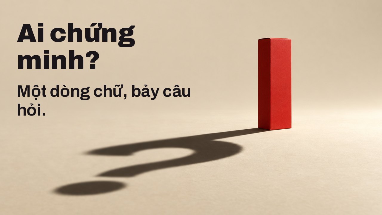 Ai chứng minh? Một dòng chữ, bảy câu hỏi. Một chiếc hộp màu đỏ mờ trơn, không có chữ nào, đứng trên nền sàn màu kem ấm dưới một ngọn đèn rọi duy nhất, gắt và thấp; cái bóng dài sắc nét của nó trên sàn tạo thành một dấu chấm hỏi.
