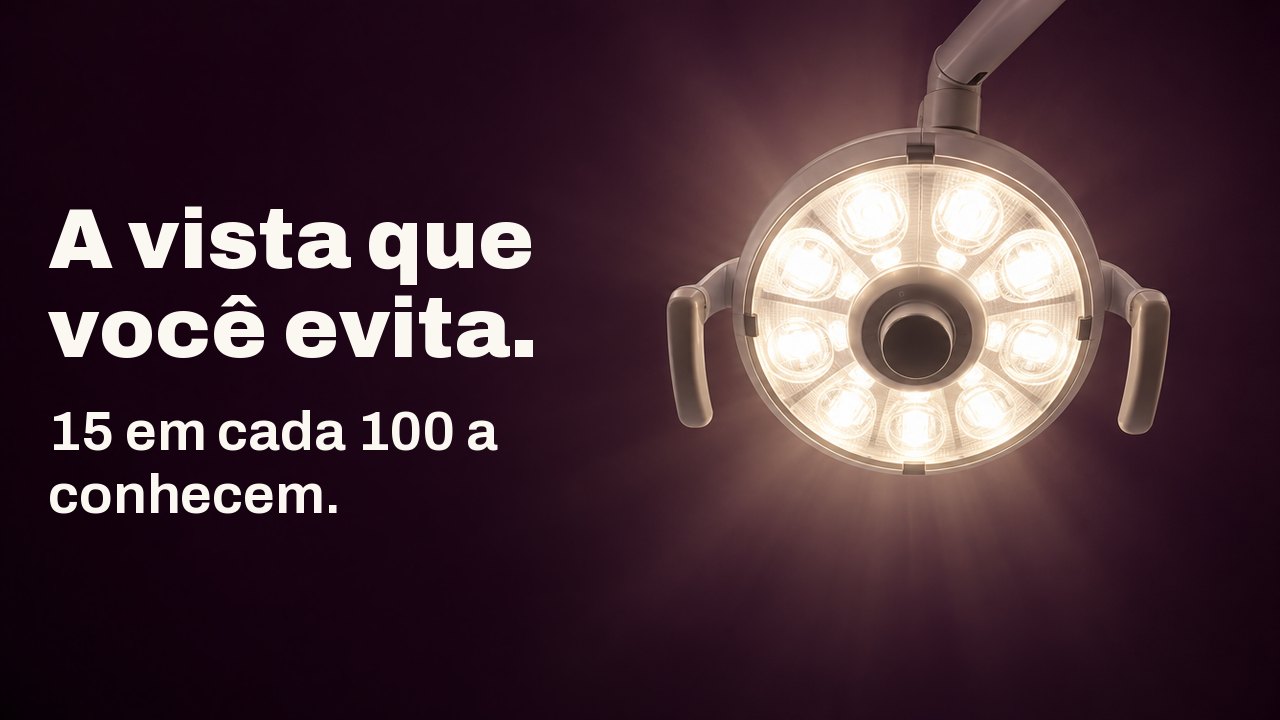 A vista que você evita. 15 em cada 100 a conhecem. A vista da cadeira do dentista, olhando direto para cima: uma luminária odontológica redonda brilha em branco quente contra um teto berinjela profundo.