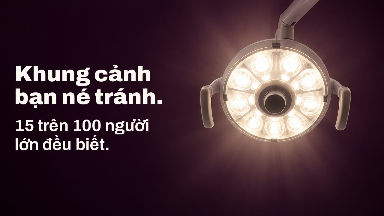 Khung cảnh bạn né tránh. 15 trên 100 người lớn đều biết. Khung cảnh nhìn thẳng lên từ ghế nha khoa: một chiếc đèn nha khoa tròn tỏa ánh sáng trắng ấm trên nền trần nhà màu tím cà đậm.