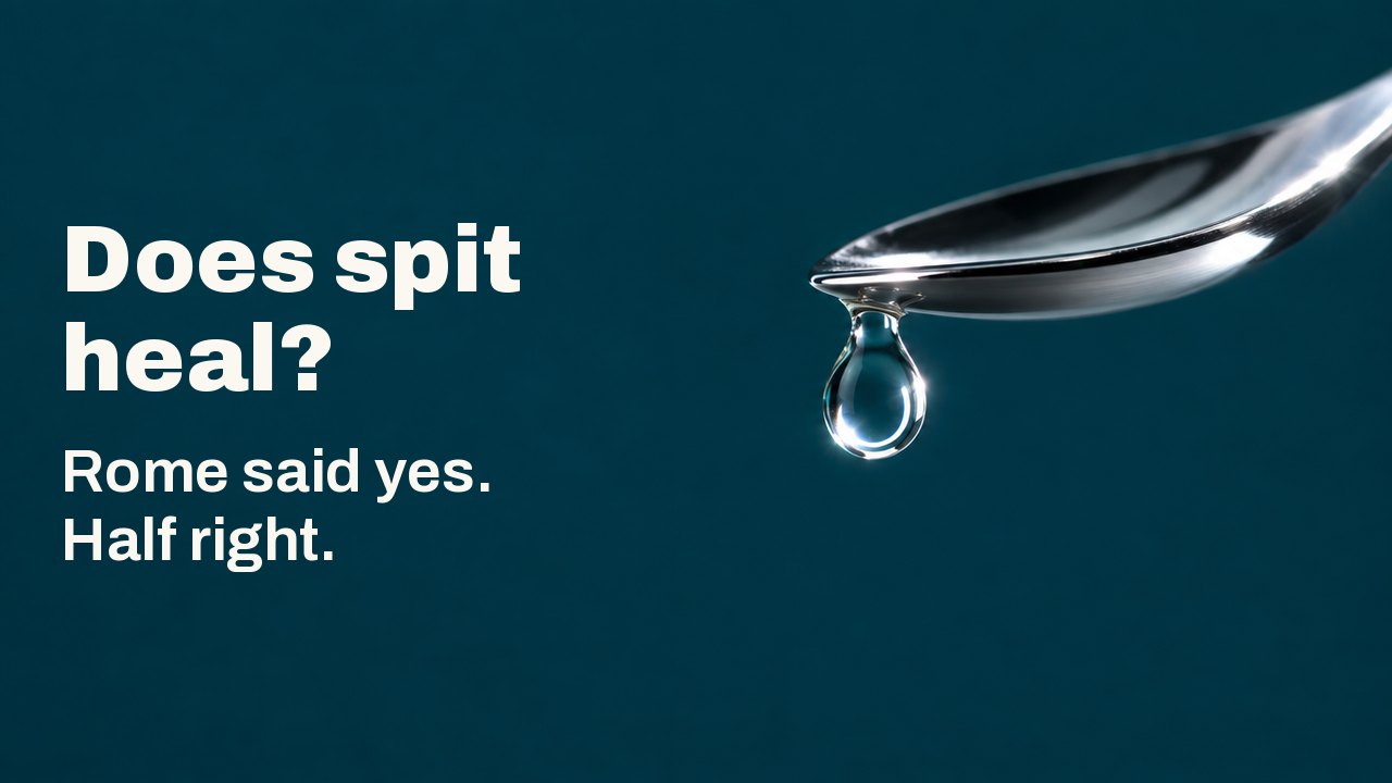 Does spit heal? Rome said yes. Half right. A single clear drop of liquid hangs from the tip of a polished silver spoon above a deep teal ground, a bright ring of light caught inside the drop.