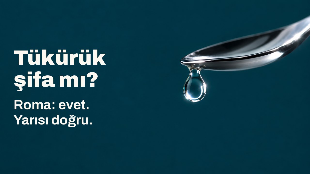 Tükürük şifa mı? Roma: evet. Yarısı doğru. Cilalı gümüş bir kaşığın ucundan, koyu camgöbeği bir zeminin üstünde tek bir berrak damla sarkıyor; damlanın içinde parlak bir ışık halkası yakalanmış.