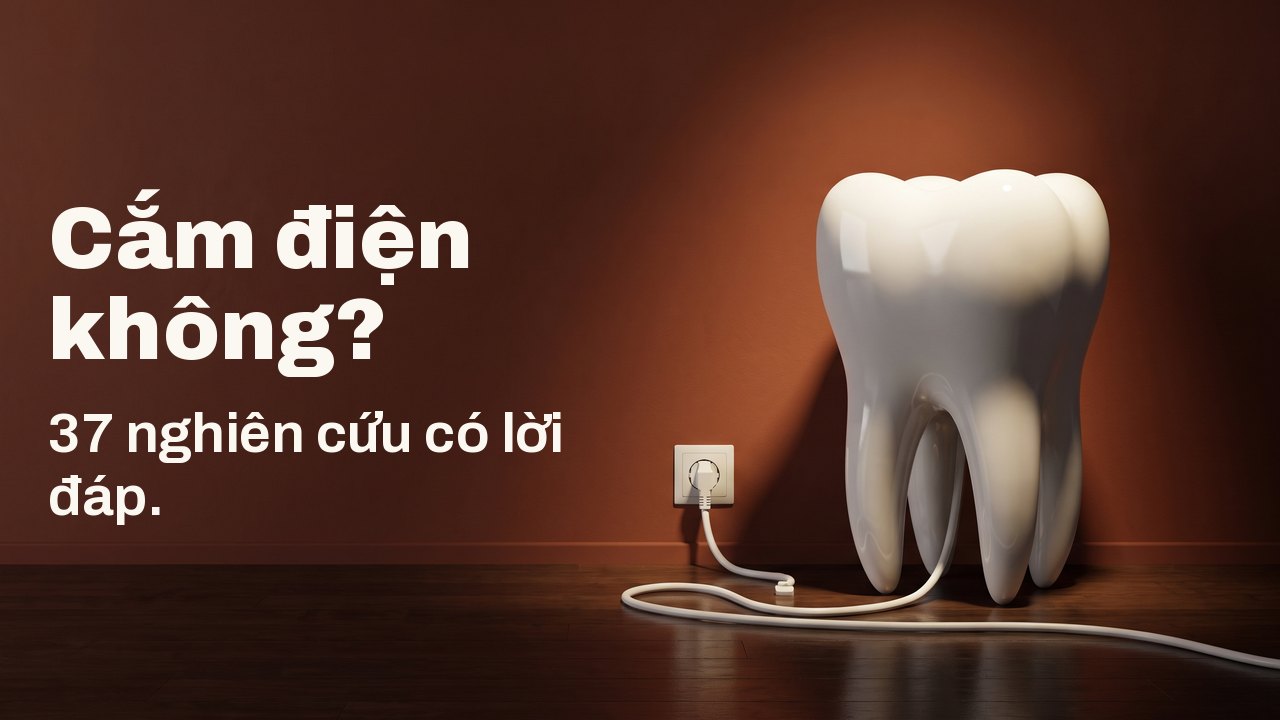 Cắm điện không? 37 nghiên cứu có lời đáp. Một mô hình răng bằng sứ trắng trên sàn gỗ, trước bức tường màu đất nung, sợi dây trắng của nó cắm vào ổ điện trên tường.