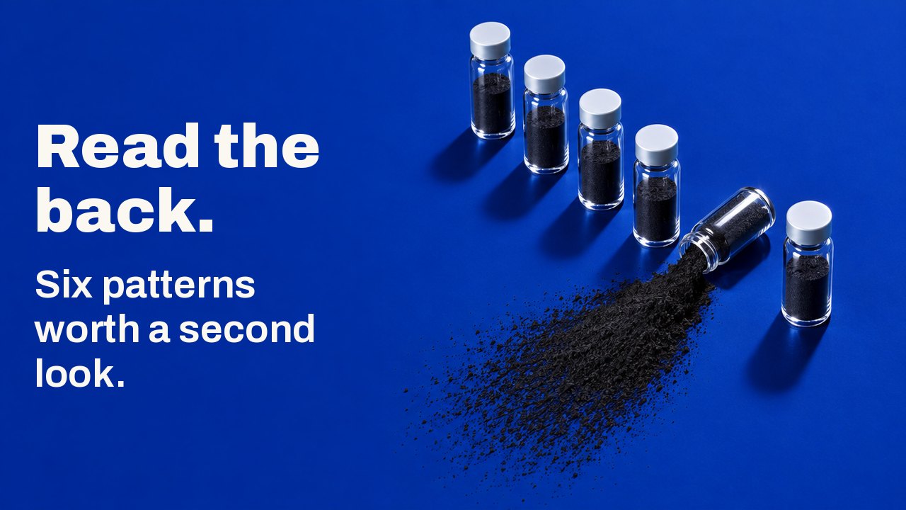 Read the back. Six patterns worth a second look. Seen from above on a deep cobalt blue surface: six small glass vials stand in a row, and one has tipped over, spilling a fan of black charcoal powder.