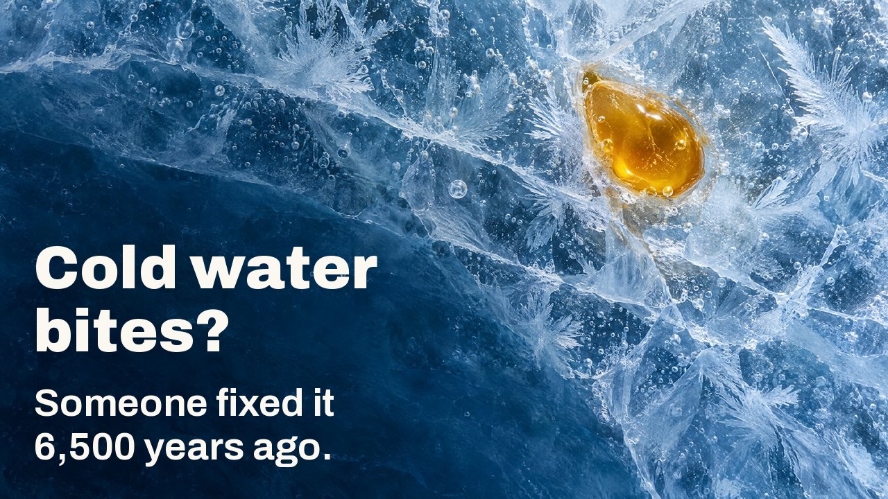 Cold water bites? Someone fixed it 6,500 years ago. Seen from above: a drop of golden beeswax frozen into cracked blue ice with frost feathers and air bubbles.