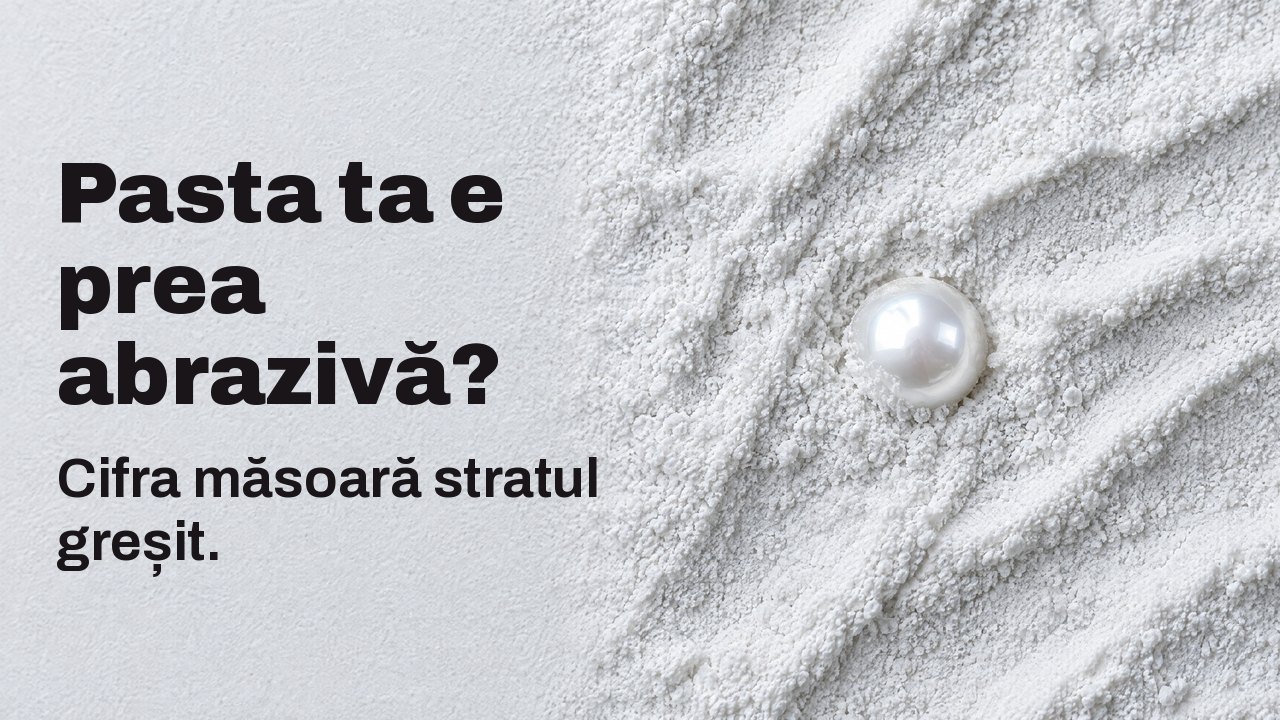 Pasta ta e prea abrazivă? Cifra măsoară stratul greșit. Văzută de sus: o singură perlă lucioasă pe jumătate îngropată în pulberea abrazivă albă și fină.