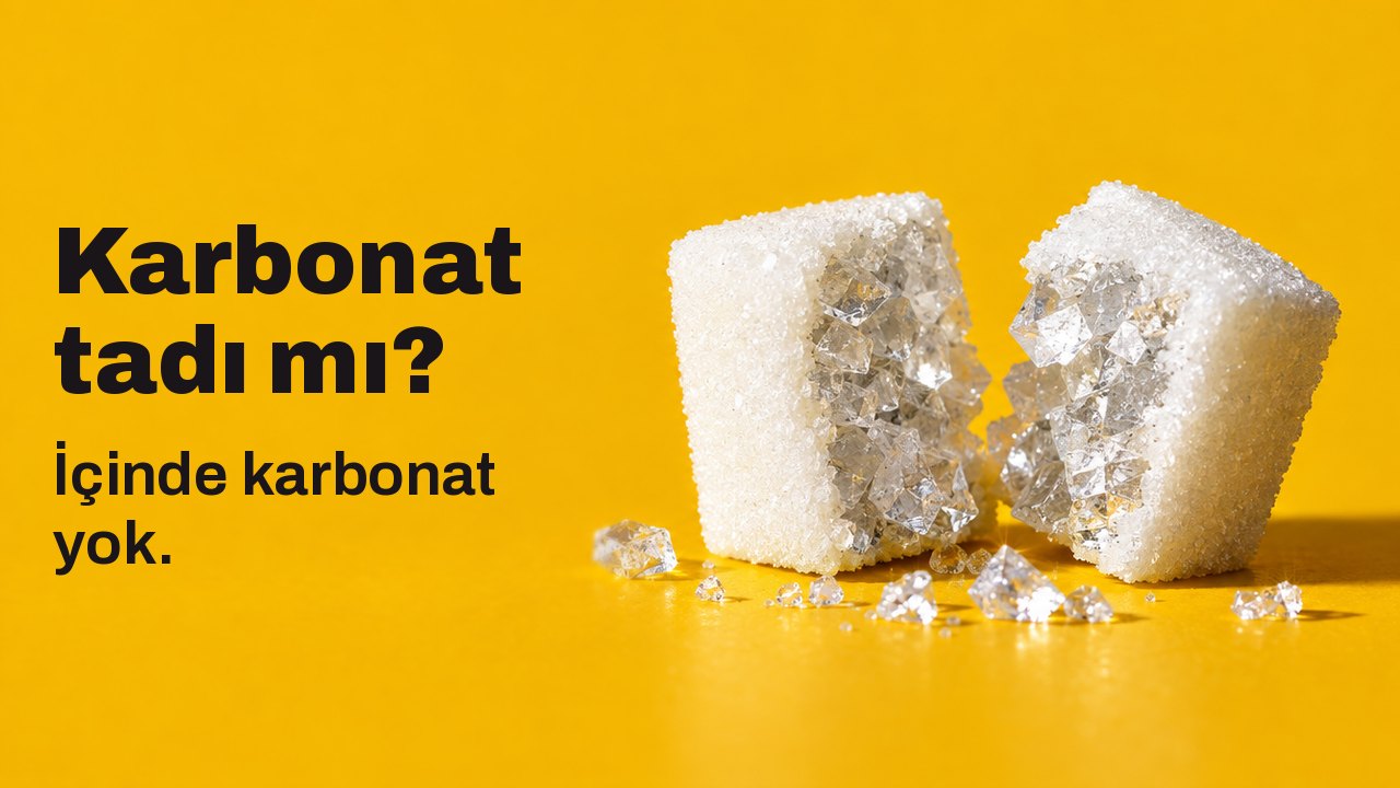 Karbonat tadı mı? İçinde karbonat yok. Sıcak safran sarısı bir zemin üzerinde masa hizasından aşırı yakın çekim: ikiye bölünmüş beyaz bir kesme şeker ve içinde şeker değil, iri, cam gibi tuz kristalleri.