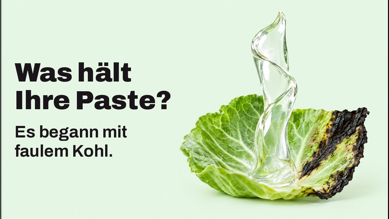Was hält Ihre Paste? Es begann mit faulem Kohl. Nah auf Blatthöhe vor blassem Mintgrund: Ein glänzendes Band aus klarem Gel steigt senkrecht aus einem frischen Kohlblatt mit schwarz gewordenem Rand und steht von selbst wie eine Skulptur.